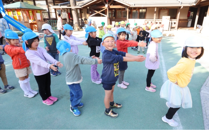 笑顔で前ならえをする園児たち